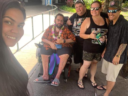 A happy group of friends takes a selfie with drinks on a sunny beach day.