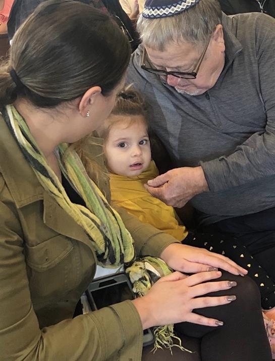 A child sits between her mother and grandfather, enjoying a warm interaction during a family visit.