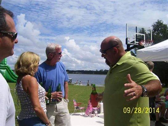 Three friends gather by the lake on a sunny day, sharing drinks and laughter.