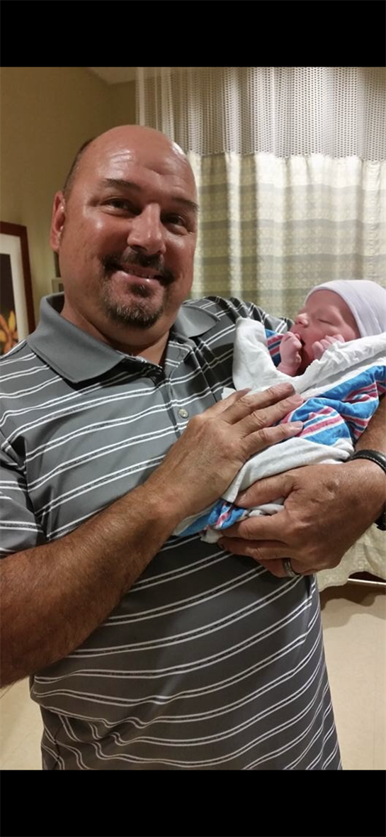 A joyful father cradles his newborn baby in a hospital, celebrating a new beginning.