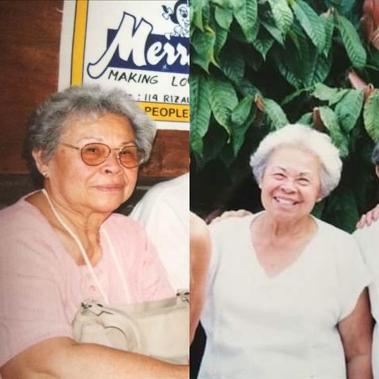 Two elderly women smile as they pose together in a lush garden, enjoying a sunny day with family.