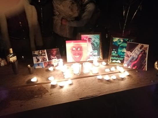 Candles light framed photos on a table, creating a warm tribute for a somber evening.
