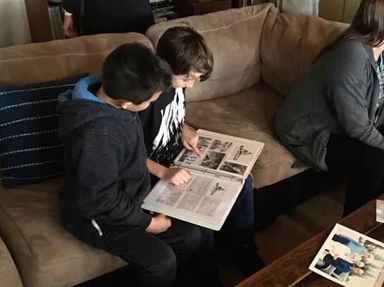 Two boys are focused on a magazine, sharing thoughts while sitting on a comfortable couch.
