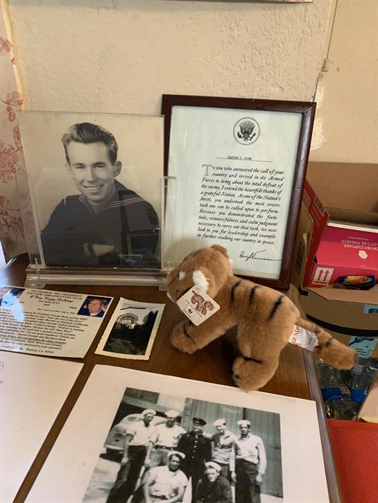 A table showcases memorabilia including a framed photograph, a certificate, and a stuffed animal.