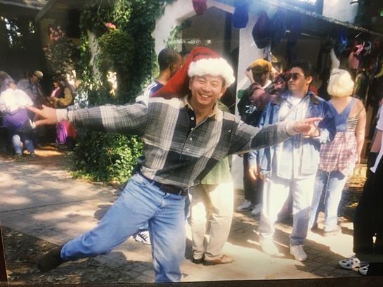 A man in a Santa hat energetically dances among a lively crowd during a festive event.
