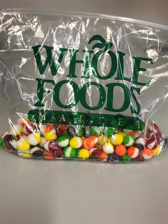 A variety of bright candies fills a transparent bag, showcasing their vibrant colors and shapes.