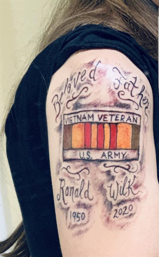 A detailed tattoo on a man's arm showcases a tribute to a Vietnam veteran father.