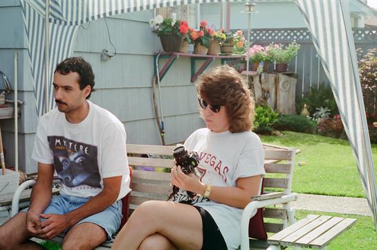 Two friends sit comfortably outdoors, sharing moments of joy and music in a vibrant backyard.