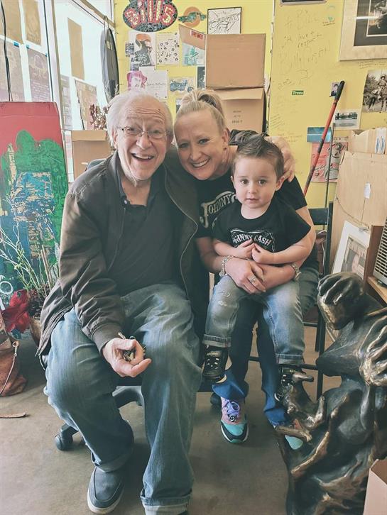 Three people share a joyful moment, surrounded by eclectic decor and memories in a welcoming space.