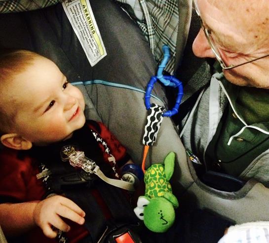 A toddler engages in a cheerful moment with their grandparent at a park, both smiling happily.