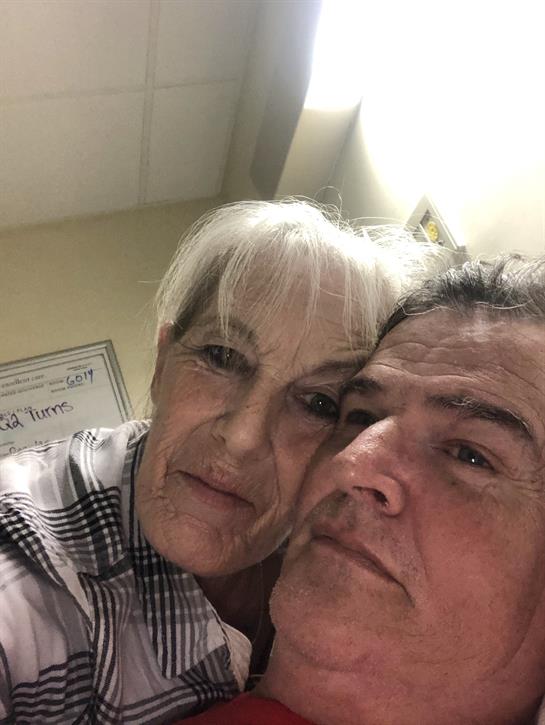 Two people share a warm embrace while smiling, enjoying their time together in a cozy setting.