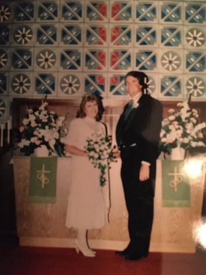 A couple stands side by side at an altar adorned with flowers, celebrating their wedding vows.