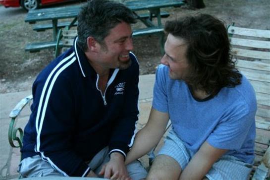 Two friends are laughing and sharing a heartfelt moment by the lake on a sunny day.