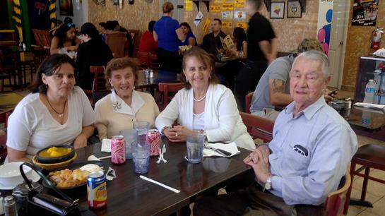 A group of four friends chats warmly at a bustling restaurant while savoring their beverages.