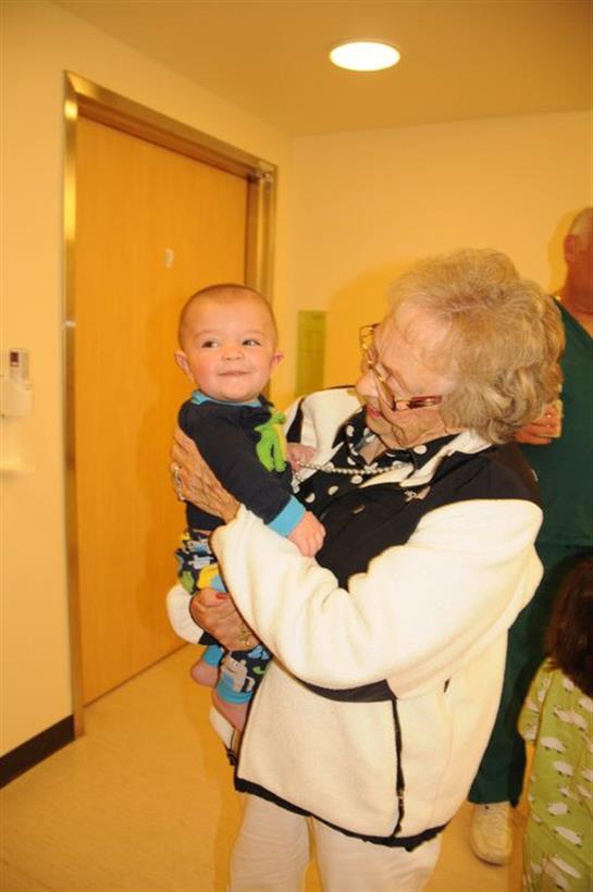 A grandmother happily embraces her young grandchild, showcasing their loving bond.