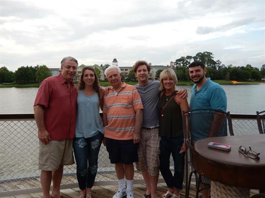 Family members share laughter and memories by the lake on a cloudy day.