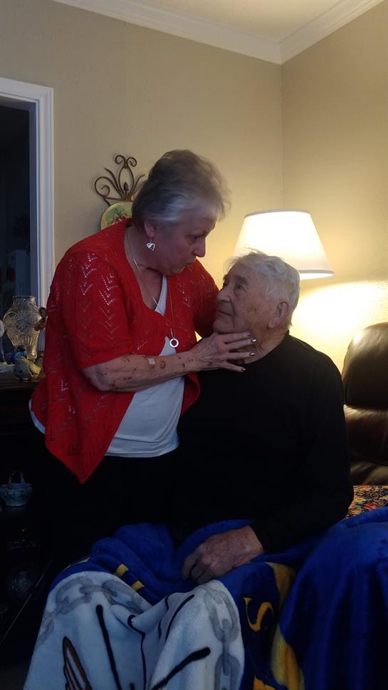 Elderly couple enjoys a heartfelt interaction while sitting on a sofa at home.