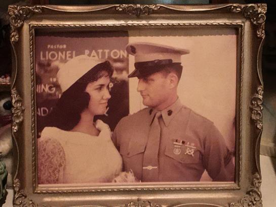 A man in military uniform and a woman in a vintage dress share a loving glance at a celebration.