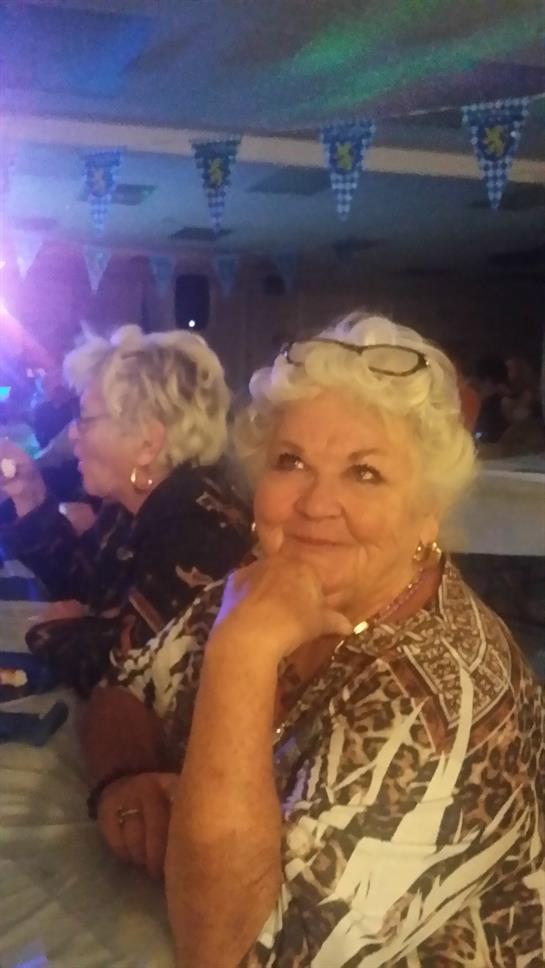 Two seniors chat at a lively gathering, enjoying music and each other's company.