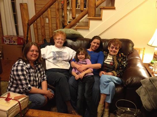 Five generations of women share smiles and laughter at a warm gathering.
