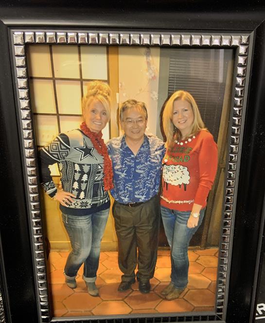 Friends pose together wearing colorful holiday sweaters in a warm, festive environment.