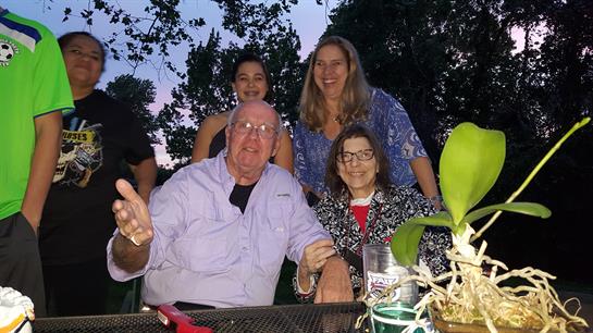 Group of friends and family share laughter and stories while dining outdoors at dusk.