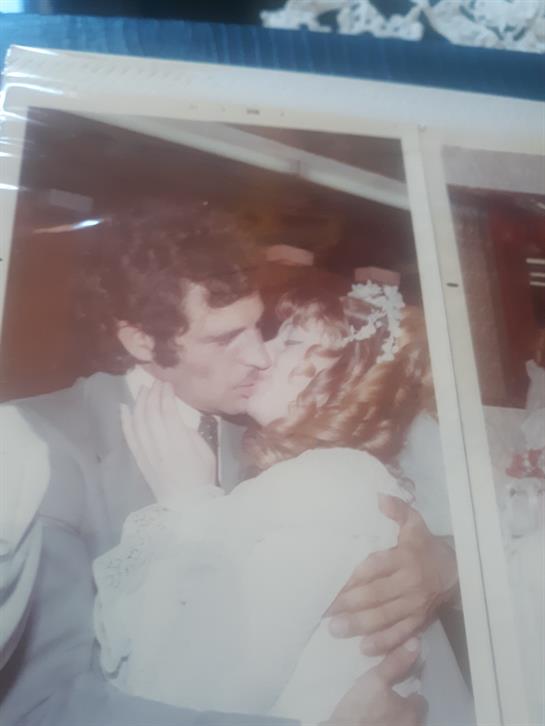 Newlyweds embrace and kiss, surrounded by friends and family, celebrating their special day.