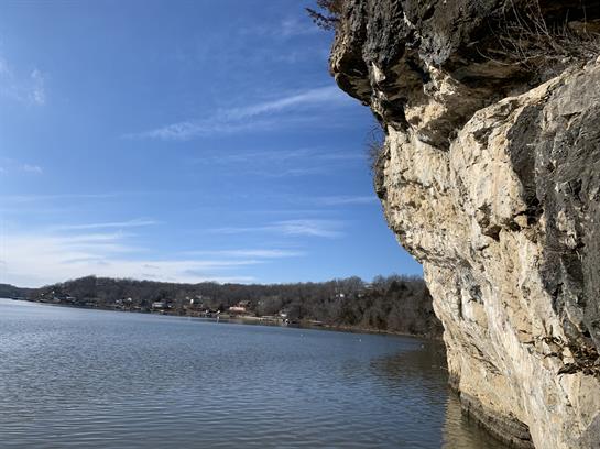 A tranquil lake reflects a blue sky while cliffs rise dramatically along the shoreline.