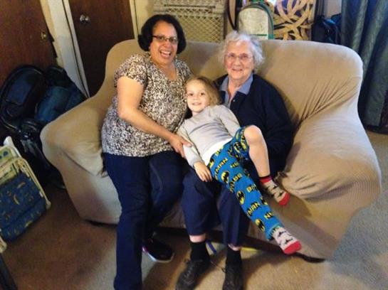 Three generations of family share a joyful moment together in a cozy living room.