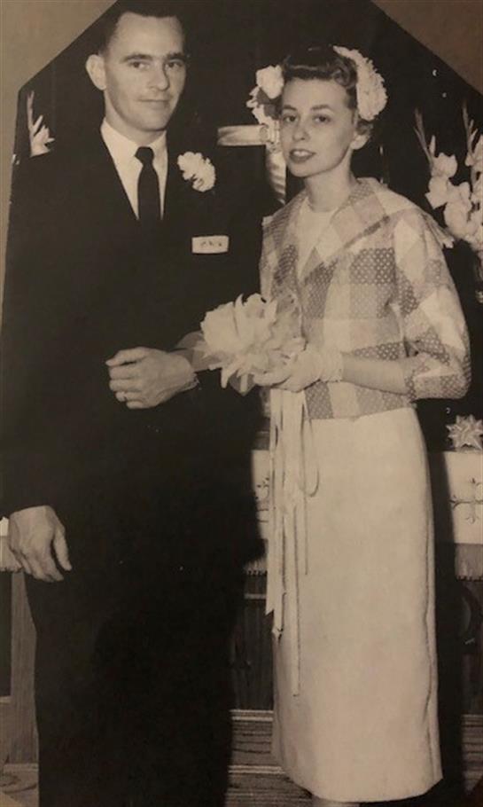Happy couple poses at a formal event, surrounded by floral decor, cherishing their moment.