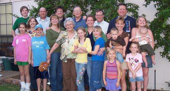 A large group of family members enjoys a sunny day together in the backyard, sharing laughter.