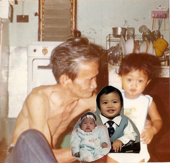 A grandfather lovingly interacts with a young child in their kitchen, with a baby portrait nearby.