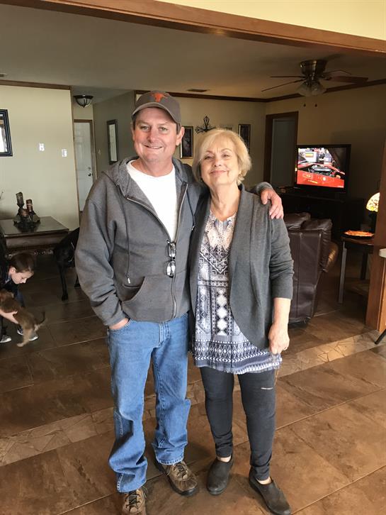 Two friends smile in a cozy, welcoming living room with comfy furniture.