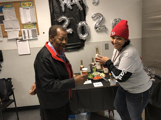 Two cheerful people share a moment with drinks in hand during a lively celebration indoors.