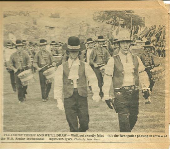 Groups of individuals in historical clothing march with drums during a lively parade.