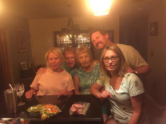 Five people enjoy a warm evening together in a cozy dining area, sharing laughter and meals.