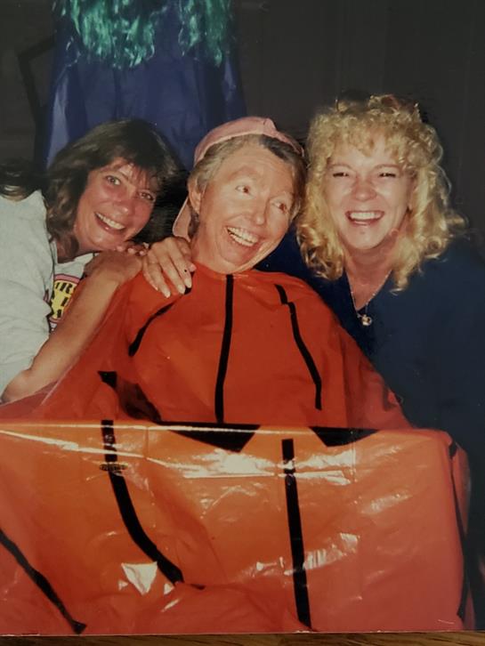 Three friends enjoy a joyful moment together while dressed in playful costumes during a celebration.