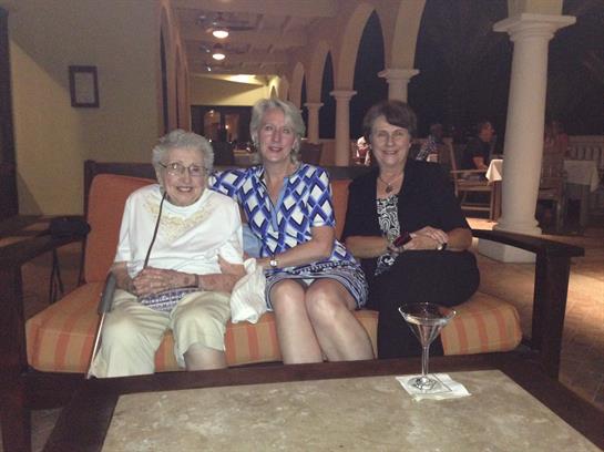 Three women sit together on a couch, sharing smiles in a warm and inviting lounge atmosphere.