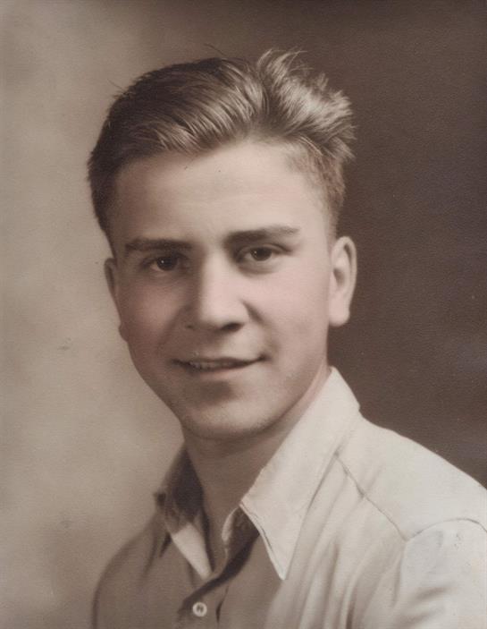 A young man poses for a classic portrait showcasing his friendly smile and stylish haircut.