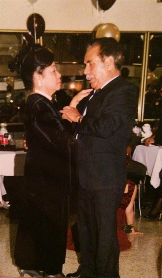 An elderly couple shares a tender dance at a lively celebration with joyful atmosphere.