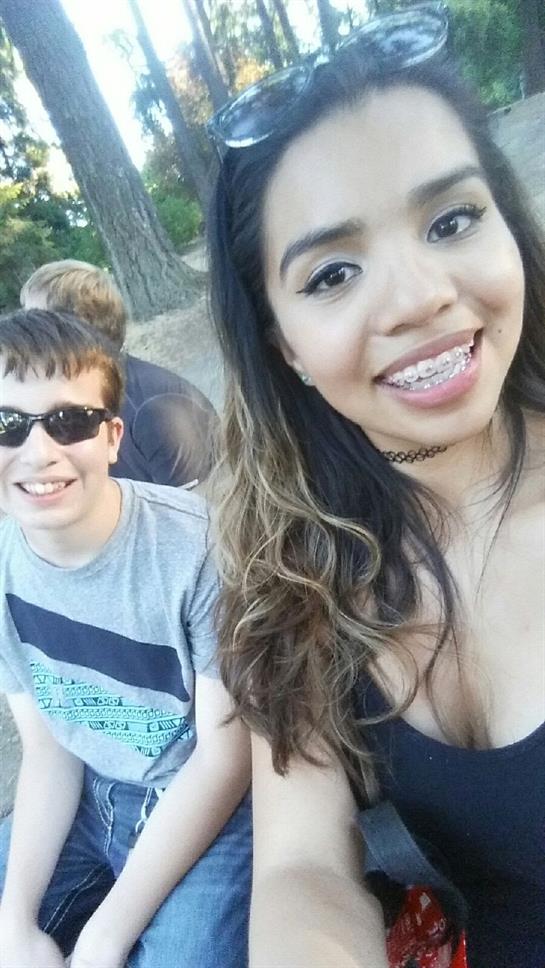 Two friends share a joyful moment outdoors, smiling for a fun selfie during a warm afternoon.