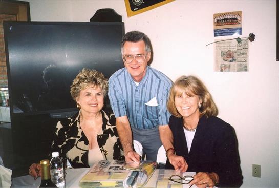 Three people enjoy a friendly gathering, smiling and interacting happily.