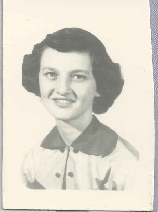 A young woman with a charming smile poses in a vintage-styled portrait dressed in 1950s fashion.
