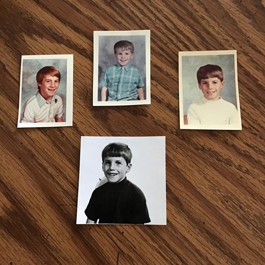 Four childhood portraits of a boy on a wooden surface, showcasing his growth over the years.