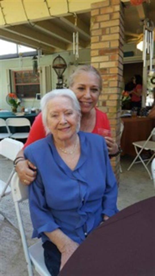 Two women share a joyful moment at a family gathering in a sunny backyard setting.