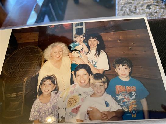 A group of seven people poses cheerfully in a wooden cabin, showcasing a warm family moment.