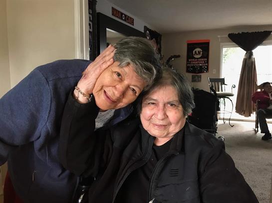 Two friends share a heartfelt embrace, radiating joy and connection in a comfortable setting.
