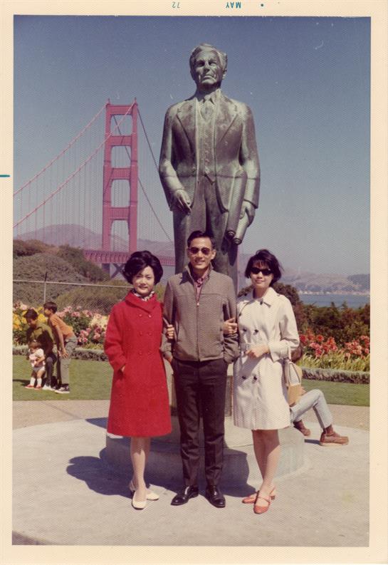 Three friends pose by a large statue with the Golden Gate Bridge in the sunny background.
