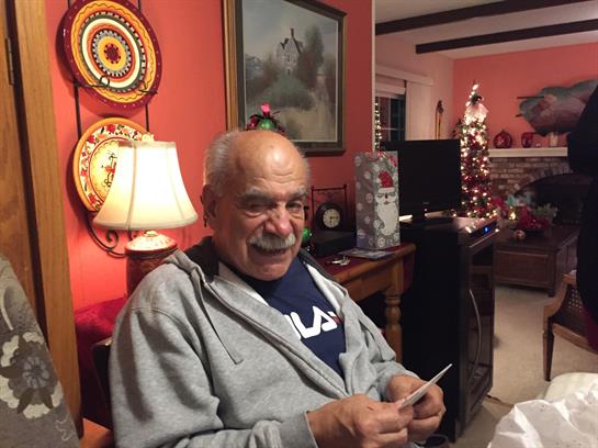Man relaxes at a festively decorated table, smiling while enjoying a cozy evening.