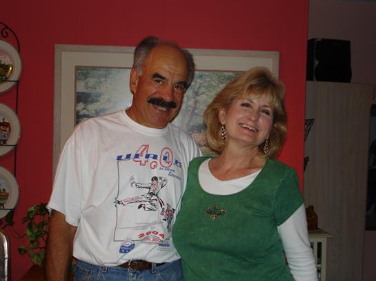 Smiling couple poses together in a warmly decorated room with a vibrant wall color.